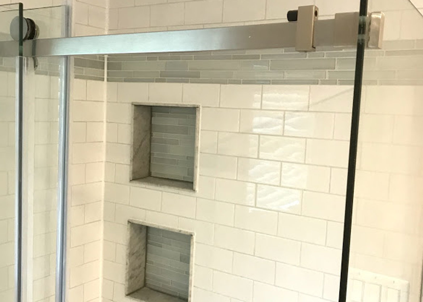 Custom tiled shower with recessed niches and glass door